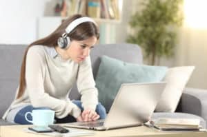 a young woman with headphones looking at the laptop screen
