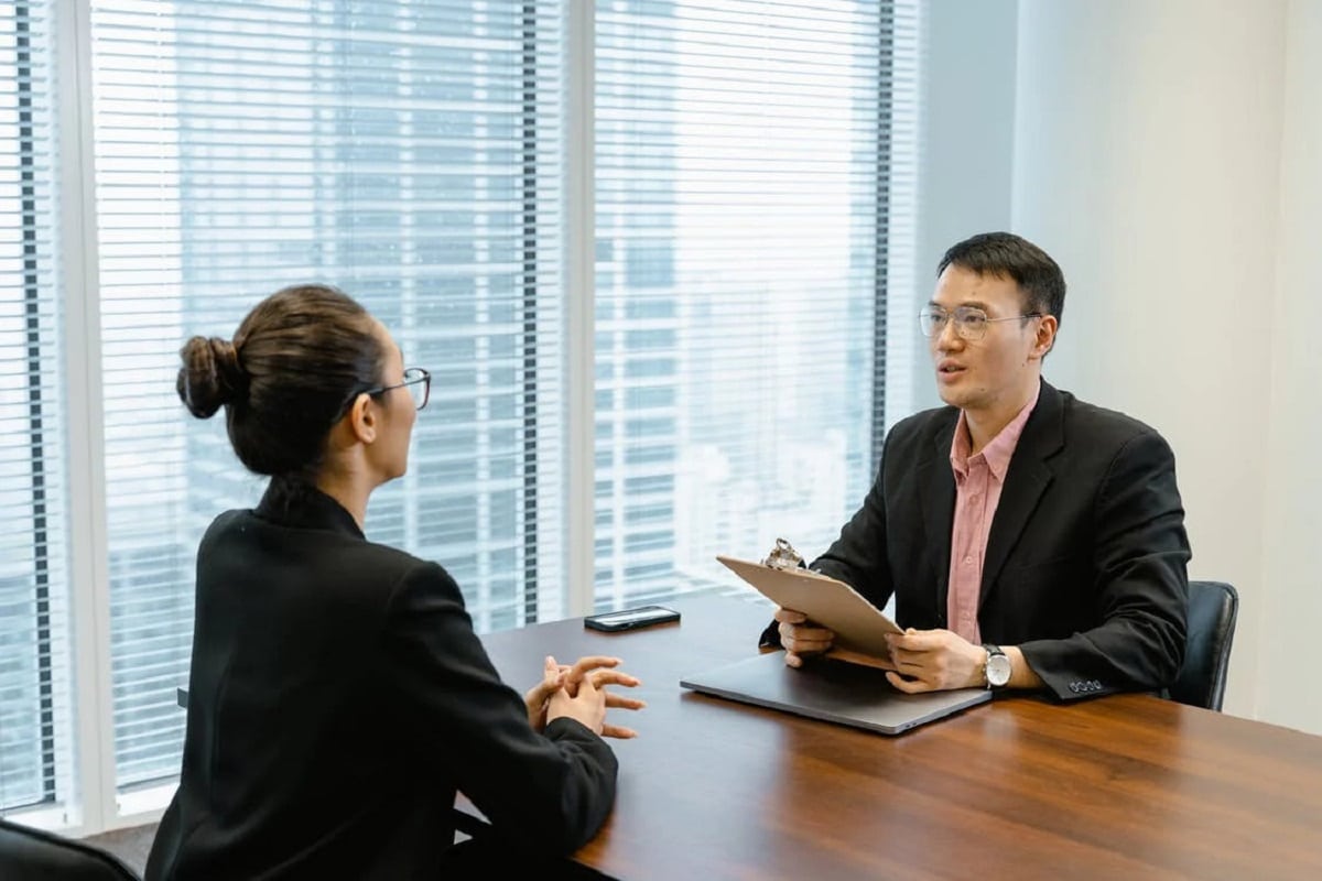 Free Man in Glasses Holding a Folder While Talking to a Woman in Suit