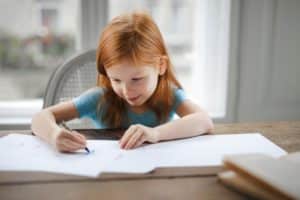a girl sitting at the table and writing