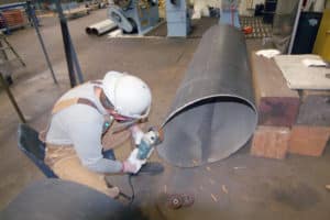 Apprentice pipe fitter grinding exhaust pipe