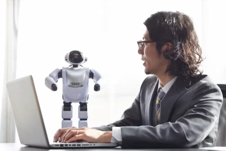 a person with laptop and robot