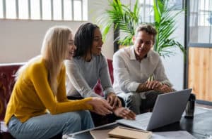 3 people smiling in front of the laptop