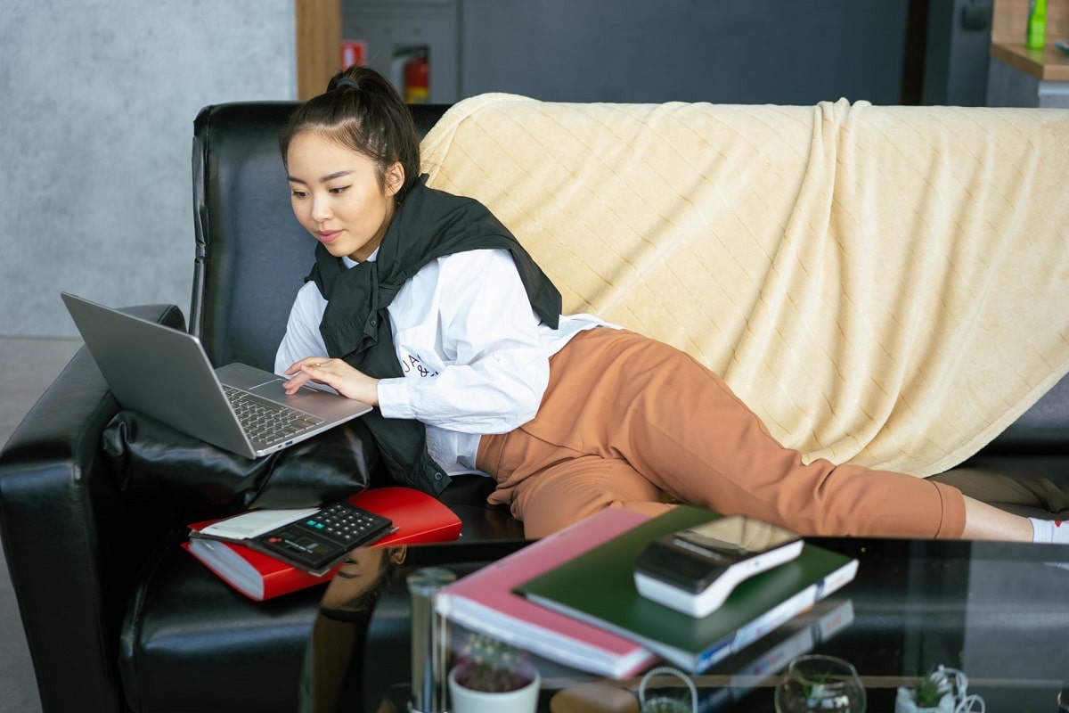 Girl lying down on sofa using laptop