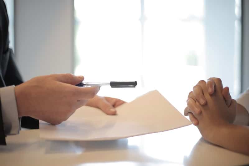 Business man giving pen to an employee to sign a contract